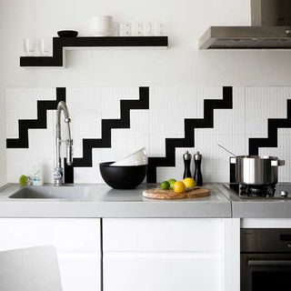 monochrome splashback tiles in geometric design white cabinets chrome worktop hob and black shelving