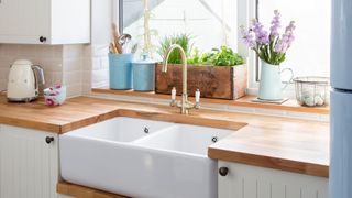 Kitchen sink with golden tap on a wooden counter top to highlight the kitchen cleaning mistake of ignoring water stains