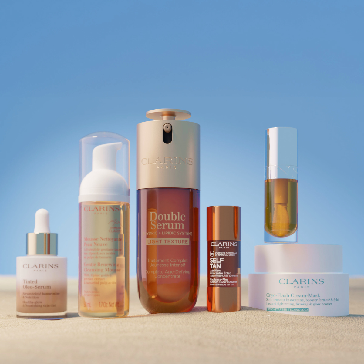 Clarins beauty products on sand with a sky blue background