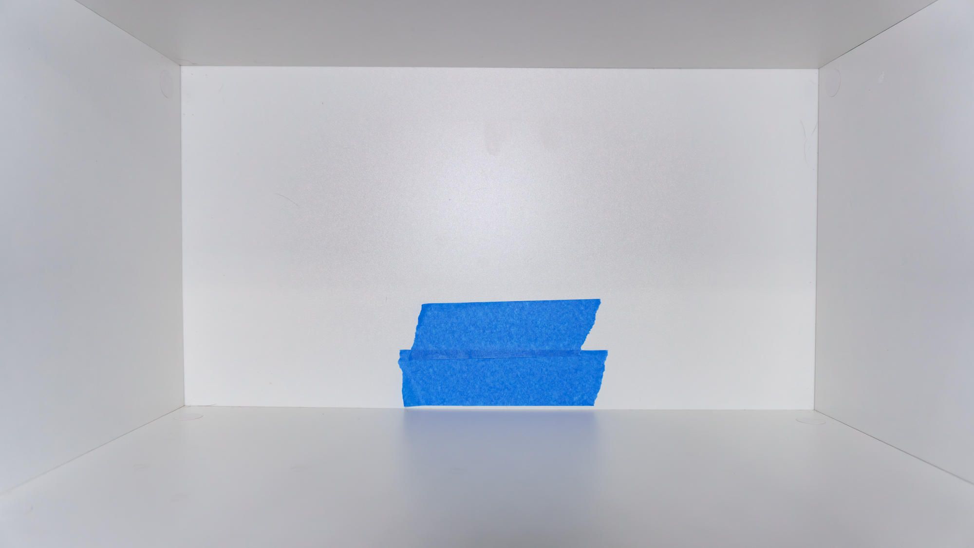 Painter's tape on the back panel of a kitchen pantry cabinet to prevent splintering while drilling