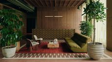 Image of a mid-century modern-style room with wooden walls, floors, and ceilings. There is a seating area in the middle with a green sofa, plants, a red rug, and white accent chairs.