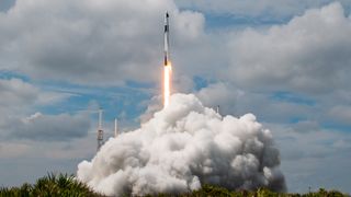 a black and white rocket launches into a cloudy blue sky