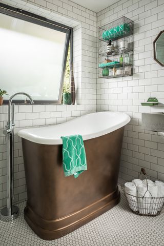 Small freestanding bath in bathroom with tiled floor and walls and shelving