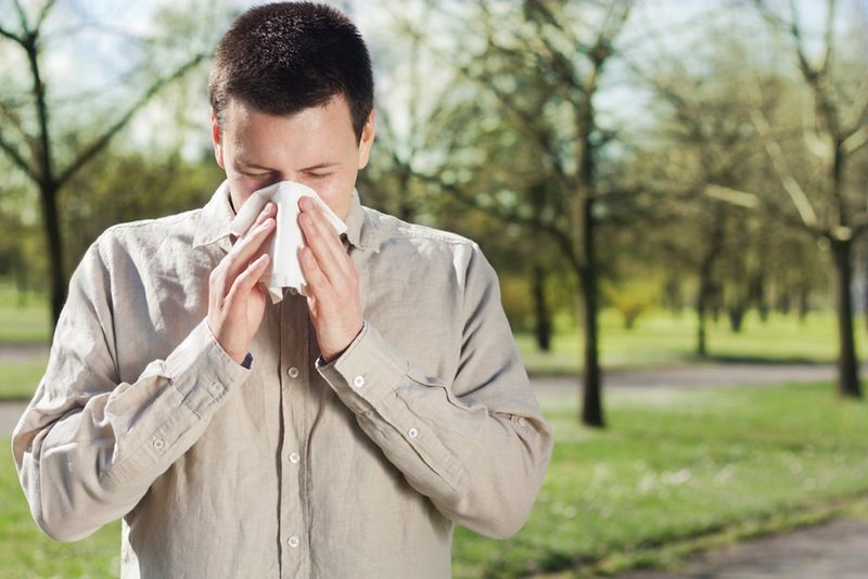 A man blows his nose into a tissue.