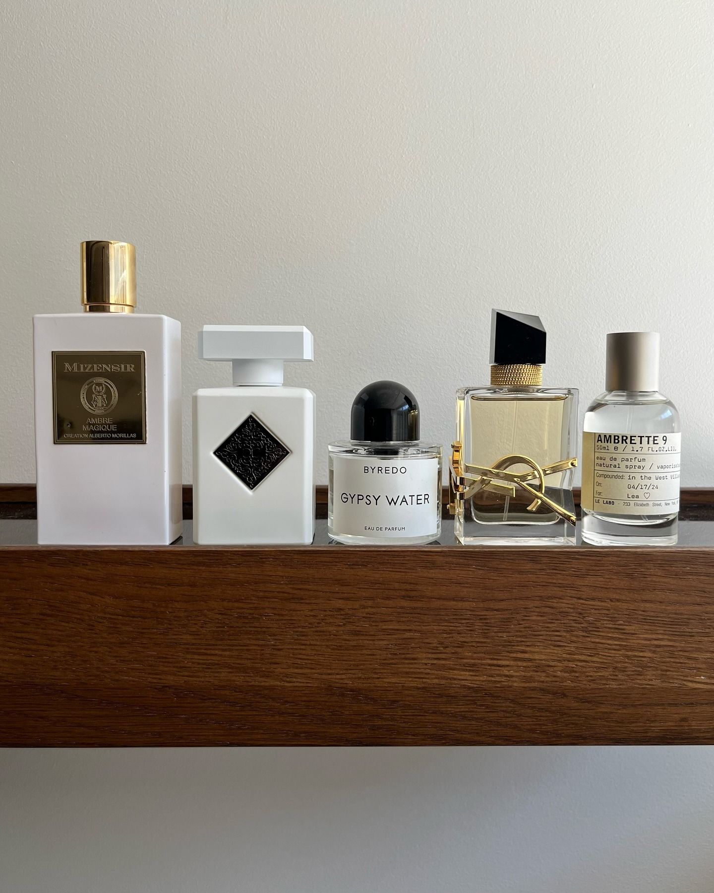 A wooden shelf with perfumes perched on top, from brands including Byredo and YSL