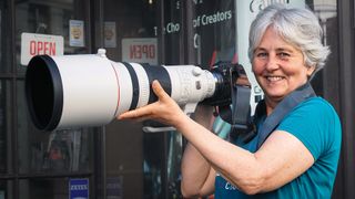 Smiling woman holding Canon RF 400mm f/2.8 lens