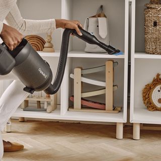 handheld vacuum being used to clean nursery storage unit