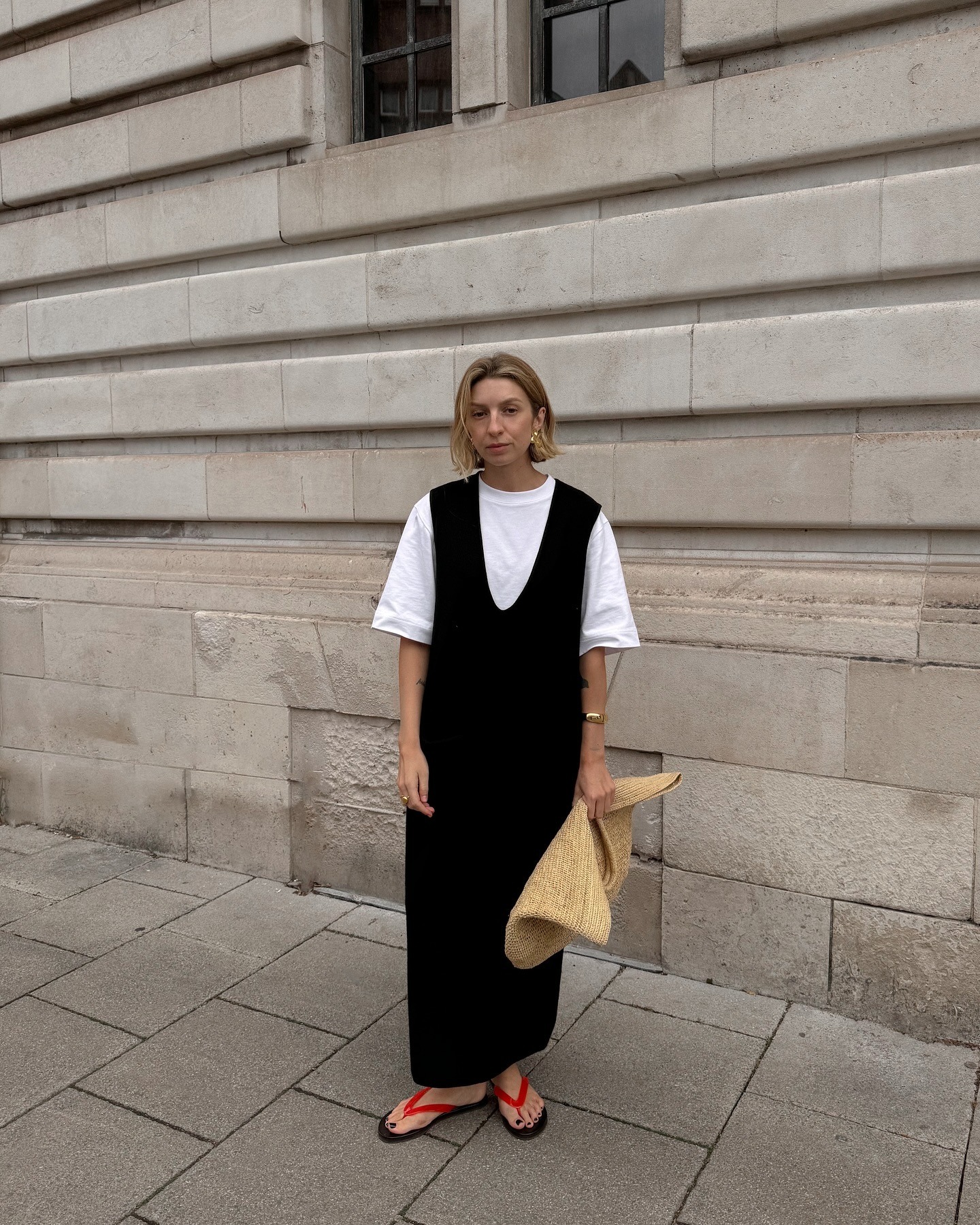 @brittanybathgate wearing a white T-shirt, black dress, and red flip-flops.