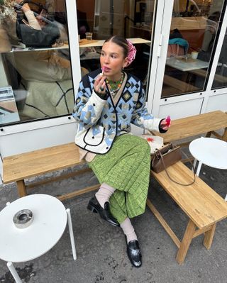 A woman wears a blue quilted jacket with a green skirt