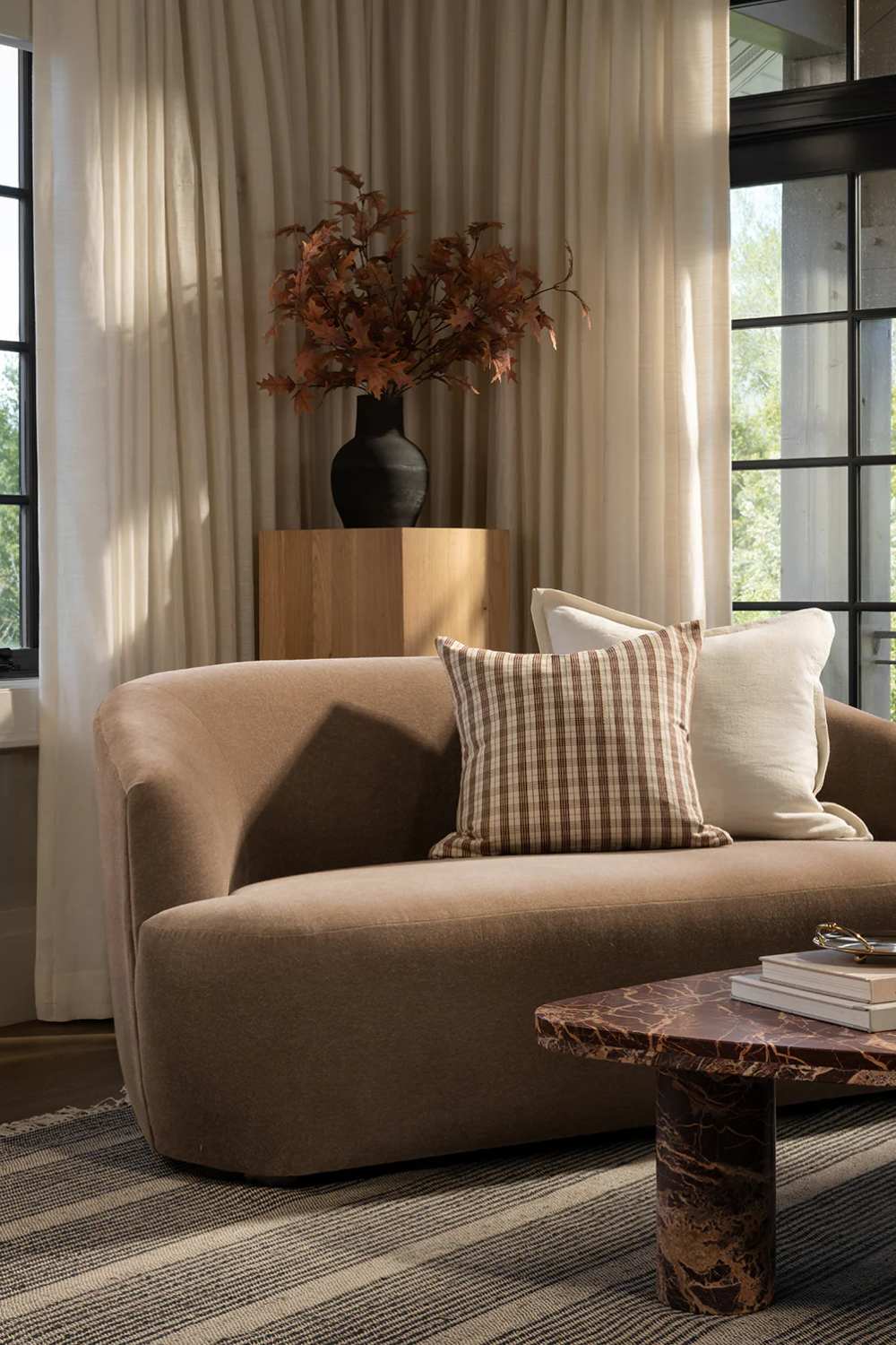 Neutral living room featuring a brown marble coffee table and curved mocha settee