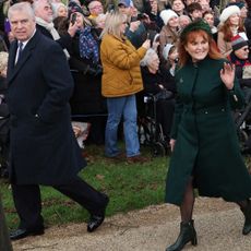 Prince Andrew and Sarah Ferguson smiling and walking to church on Christmas waving to crowds with people gathered behind them