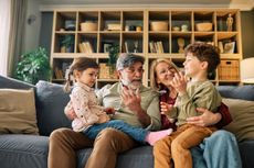 Two grandparents looking after their grandchildren on sofa