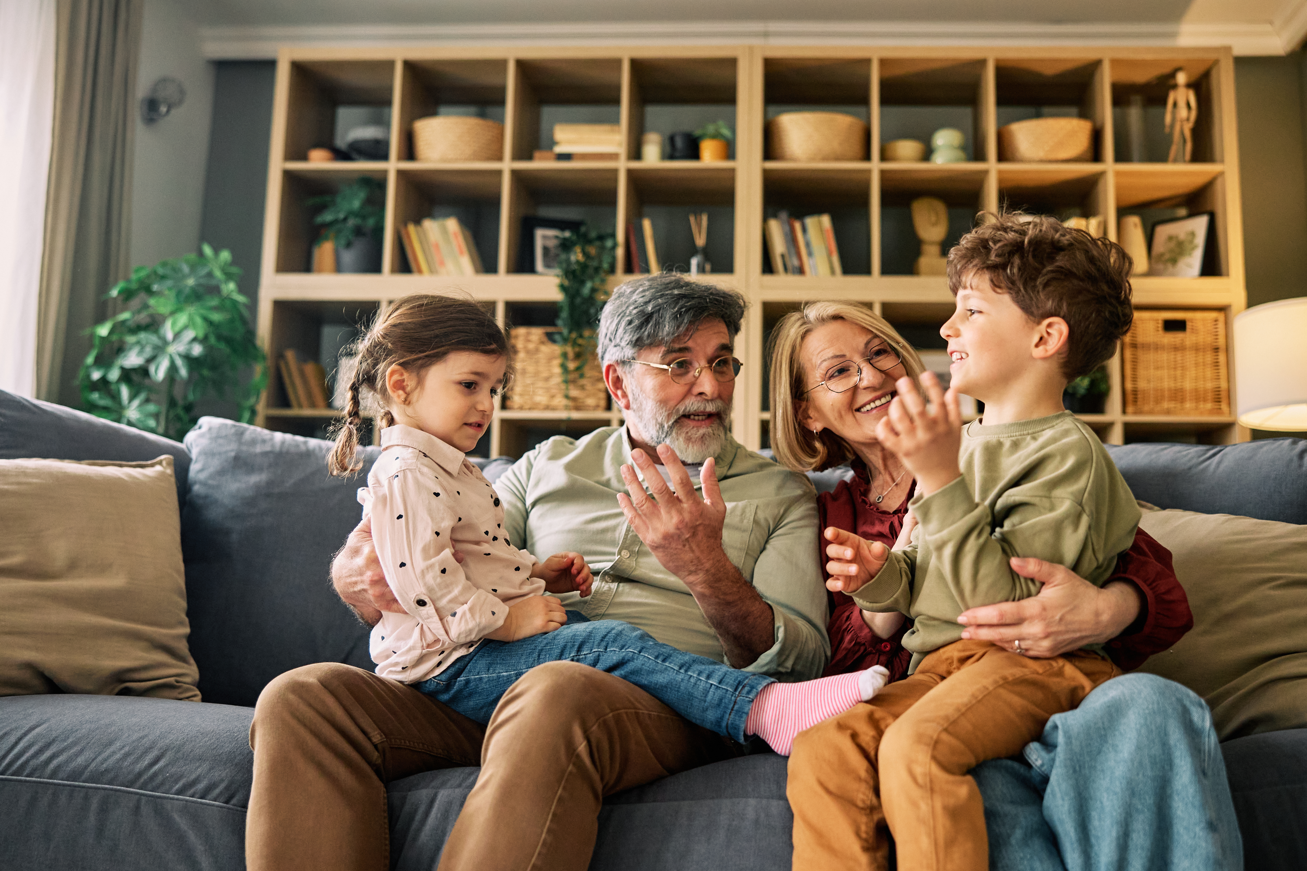 Two grandparents looking after their grandchildren on sofa
