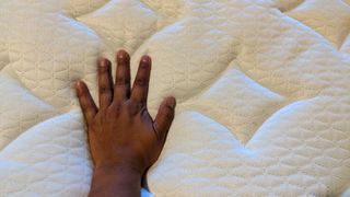 Person's hand resting on the gel-foam Ghostbed Luxe mattress