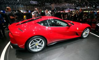 A red Ferrari 812 Superfast car on display in a car show photographed from the side with people in the background