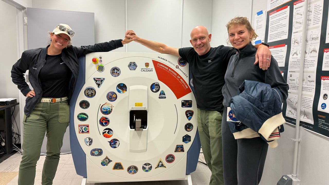 four humans stand next to a bone scanner