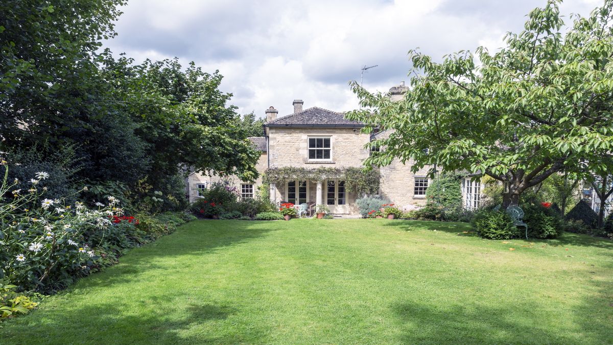 Long garden with wide lawn surrounded by trees