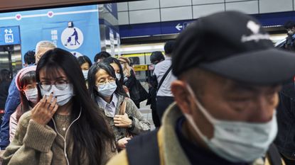 Commuters wearing face masks board a train in Taipei