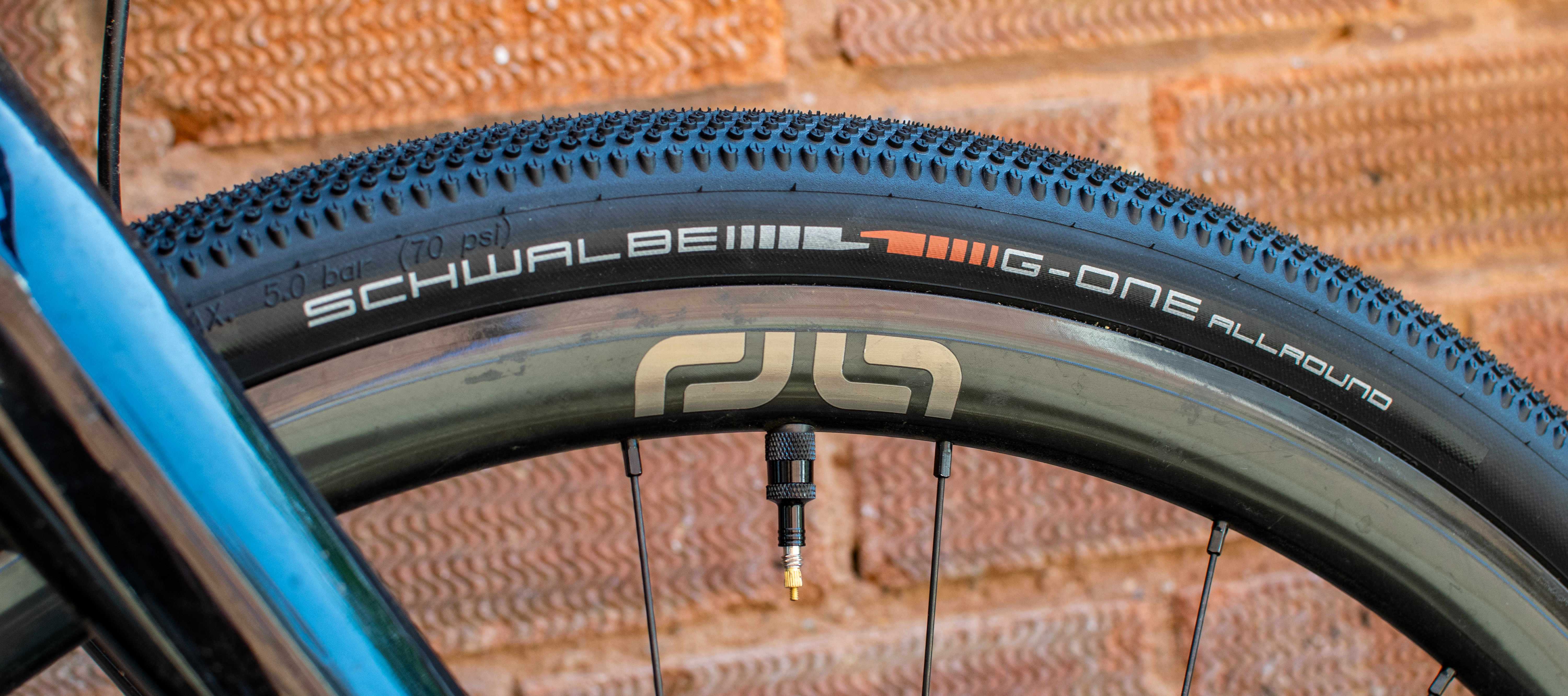 A Schwalbe G One All Round tyre in front of a brick wall 