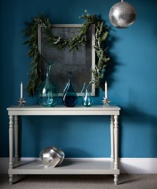 Blue living room with white console table a selection of blue glass vases, silver swirl box, Eucalyptus and rosemary garland