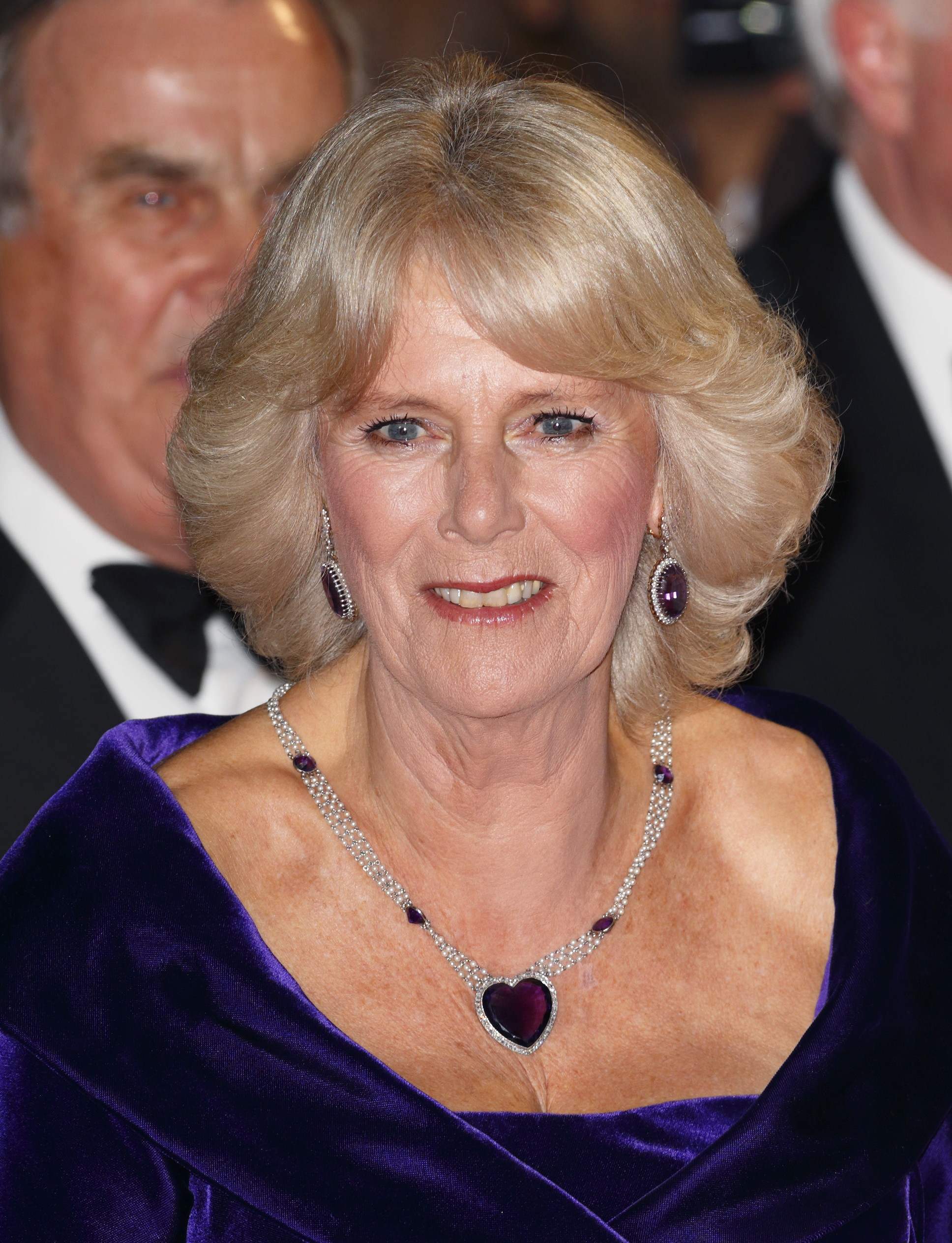Queen Camilla wearing a purple heart necklace and gown at the premiere of Skyfall
