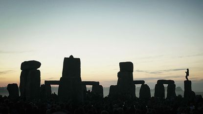 A man stands on top of one of the stones in Stonehenge on summer solstice
