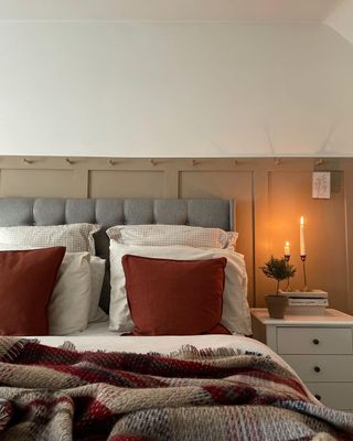 A beige bedroom with grey bedhead and red pillows
