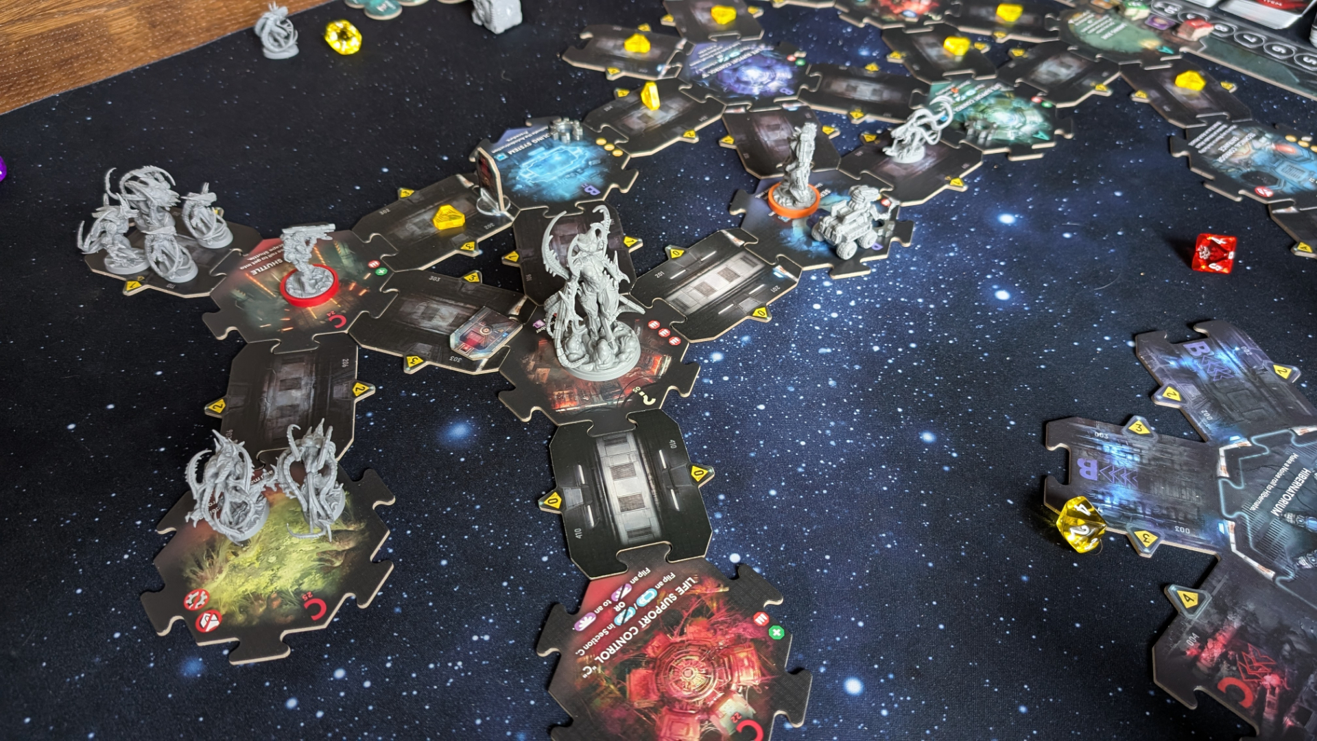 Nemesis: Retaliation pieces, board tiles, and tokens on a gaming table with a starry effect