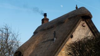 thatched roof with smoke coming from chimney