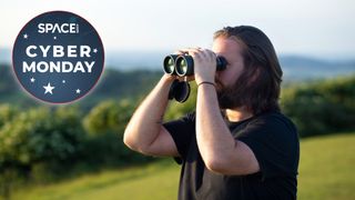 Man observes with binoculars atop green hills with cyber monday deal logo