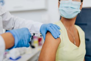 A person getting a flu shot while wearing a face mask.