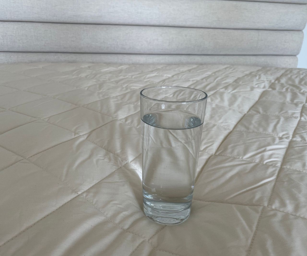 Woolroom Deluxe Washable Mattress Topper with a glass of water on it