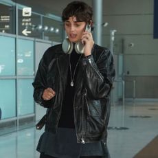 Taylor Hill leaves the airport wearing black trousers with boat shoes and a black leather jacket.