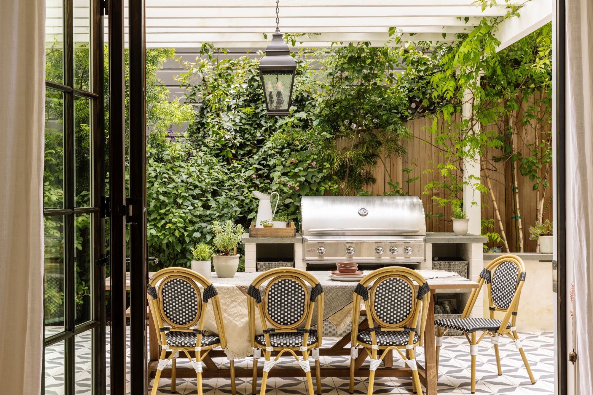 a bistro outdoor kitchen with a large dining table and a barbecue behind