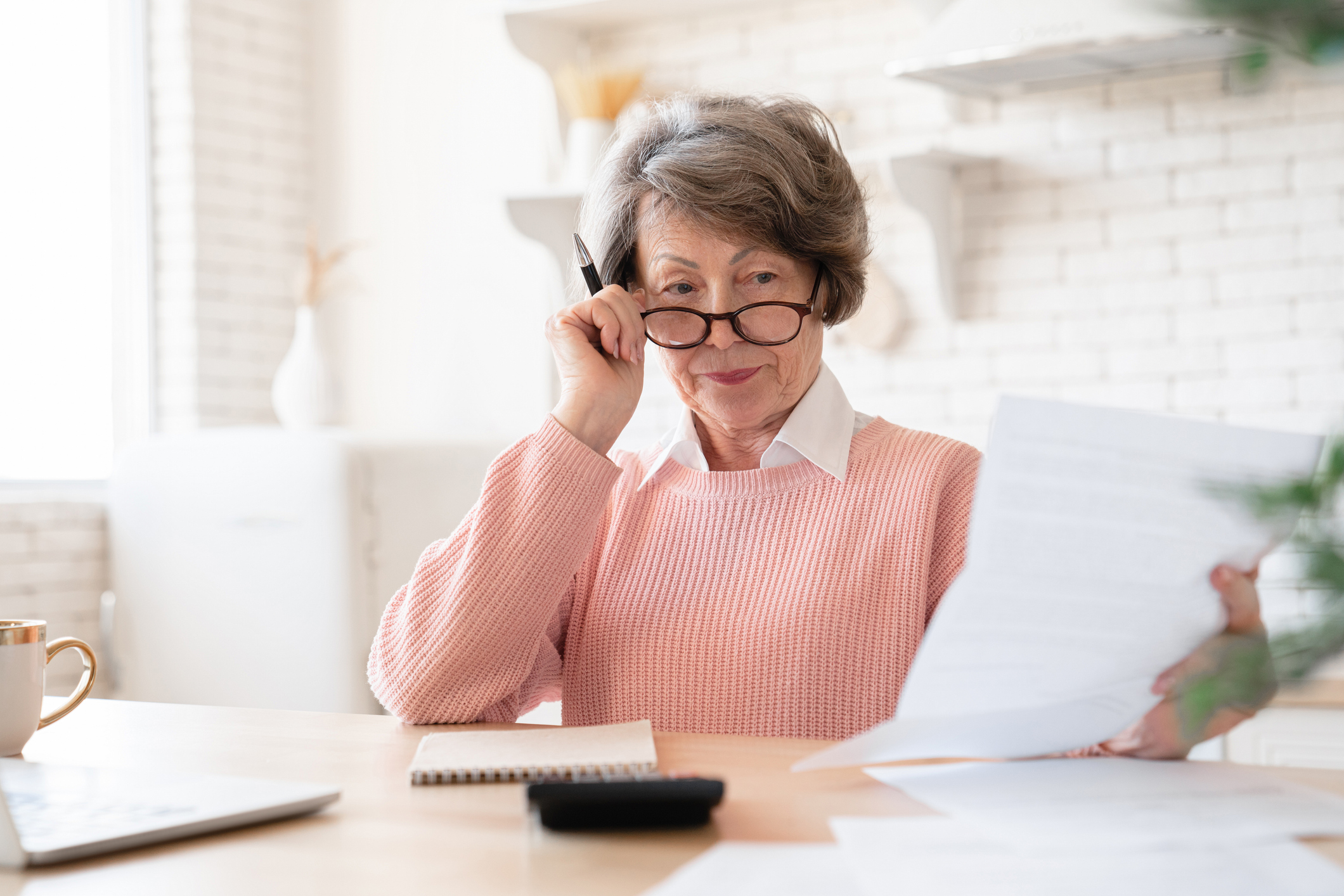 Woman wearing glasses reading paperwork to find her lost pension