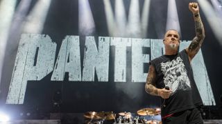 Phil Anselmo onstage in 2023, raising a fist with the Pantera logo behind him