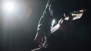 Man playing electric guitar in moody setting