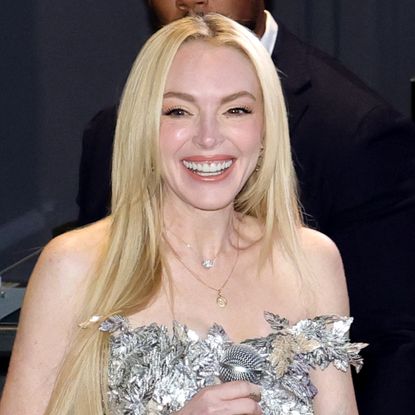 Lindsay Lohan wears a metallic strapless top, white pants, a Cartier watch, and carries an Hermes Kelly bag