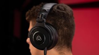 Person wearing Atomos StudioSonic headphones against a black and red background