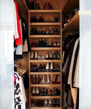 Shoes organized onto a shelving unit at the back of a large closet