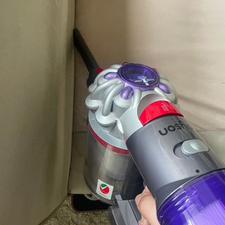 Using the Dyson V8 Absolute crevice tool down a beige sofa