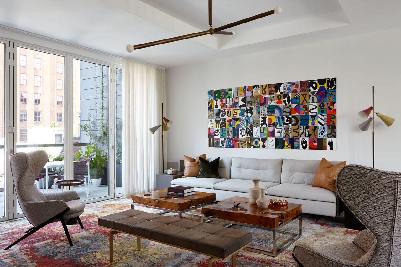 A mid century modern style living room with white leather sofa, wing back chairs and burlwood coffee tables