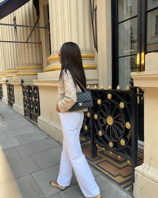 @symphonyofsilk wearing a black Chanel flap bag with white jeans and ballet flats in Paris