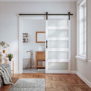 A white and glass barn door opening to a powder room