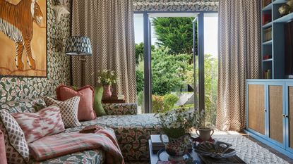 a pattern drenched living room in London by designer Elizabeth Hay with patio doors onto the garden and a blue media wall