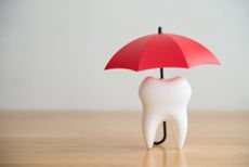 Red umbrella covers white clean tooth on white background copy space