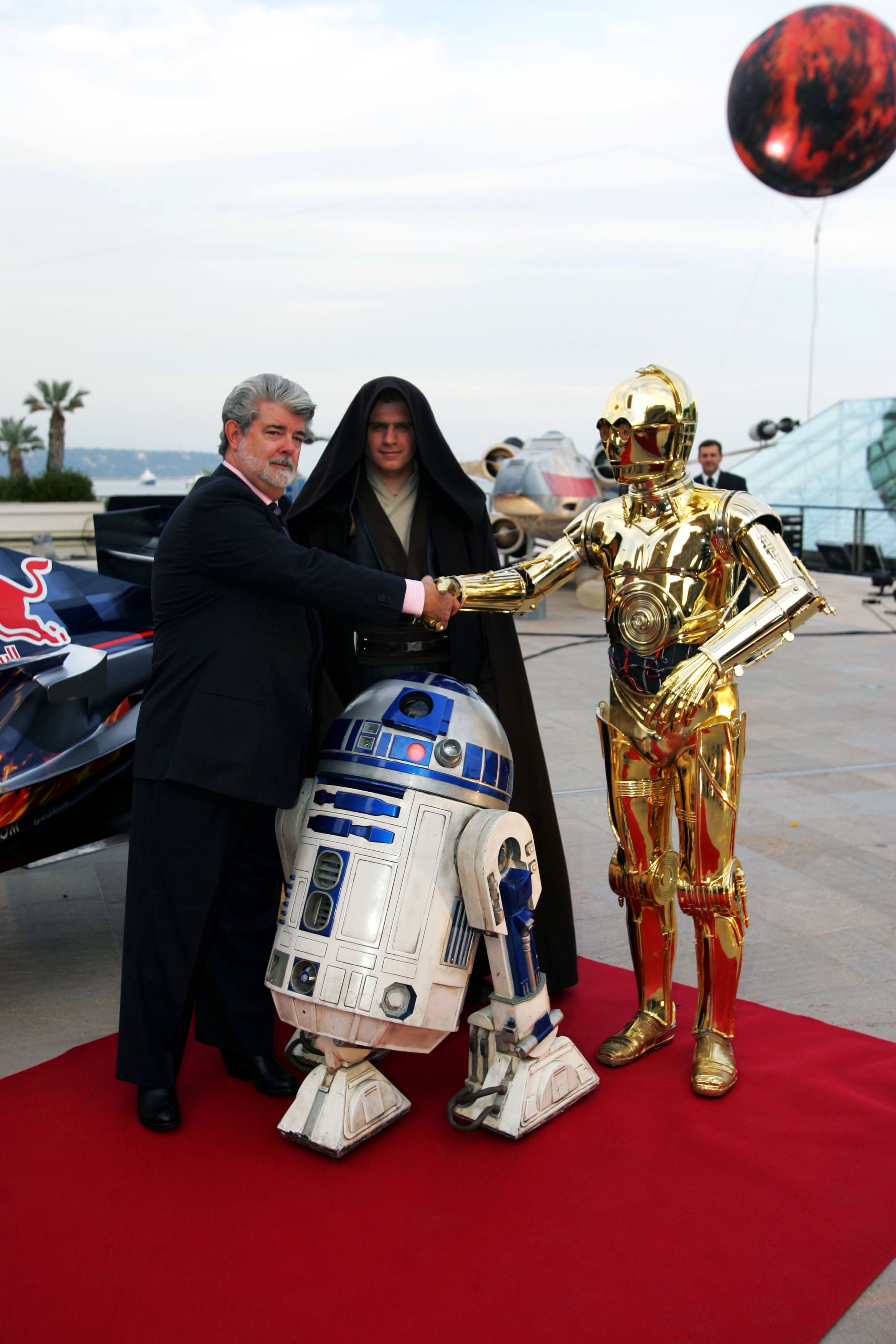 George Lucas poses with Star Wars characters on the red carpet