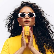 Woman wearing sunglasses and holding the Vacation body mist