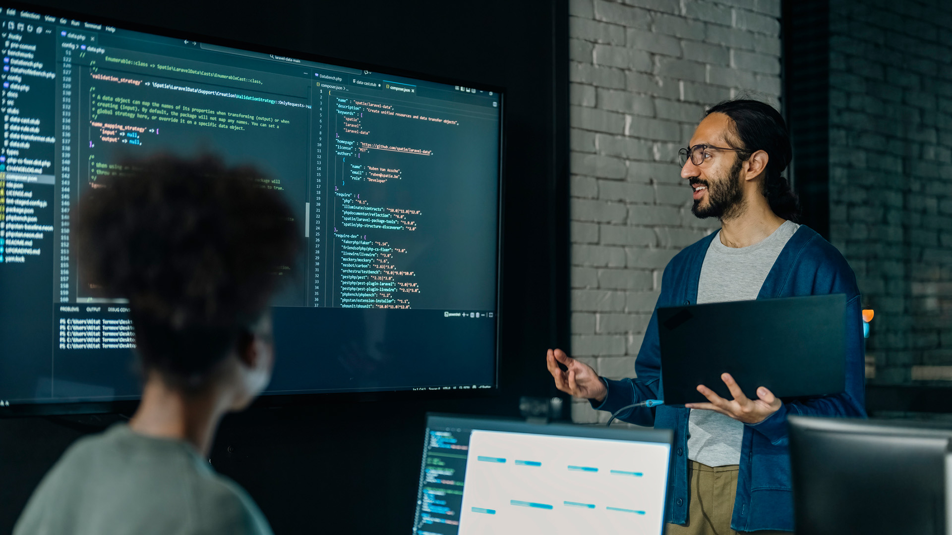 A software engineer doing a presentation on code to a younger worker, to represent upskilling and reskilling.
