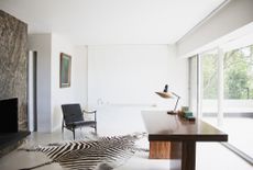 contemporary home office with wooden desk, wall of windows, and zebra hyde rug
